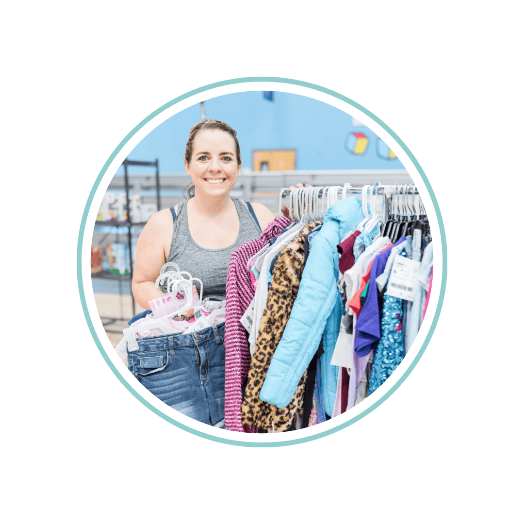 Two masked moms—one holding a child with a mask, the other pregnant—shop for their families at the local JBF sale.